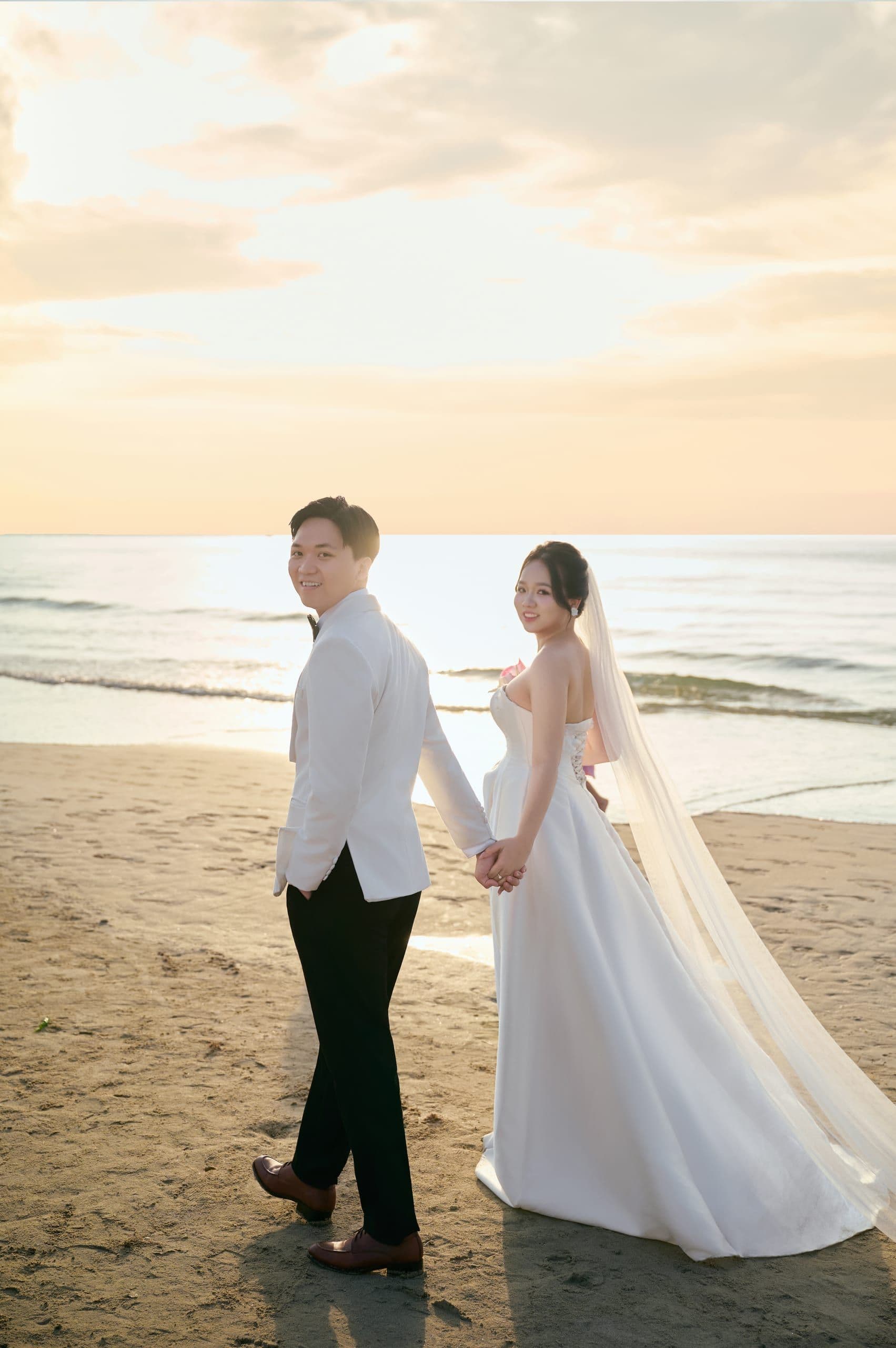 Cô dâu và chú rể dạo biển hoàng hôn